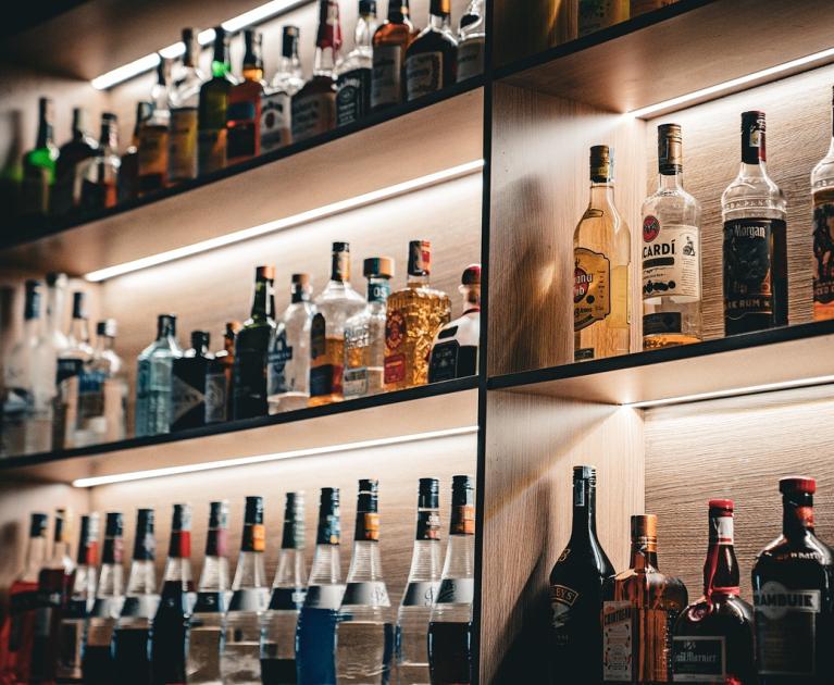 Illuminated shelves of liquor bottles, an elegant and sophisticated atmosphere.