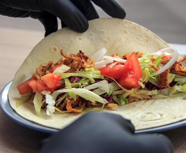 Delicious taco with meat, lettuce, and tomatoes, prepared with care.