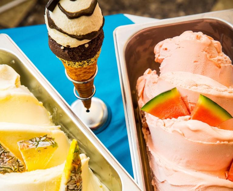 Creamy, colorful ice cream with fresh fruit on a blue table.