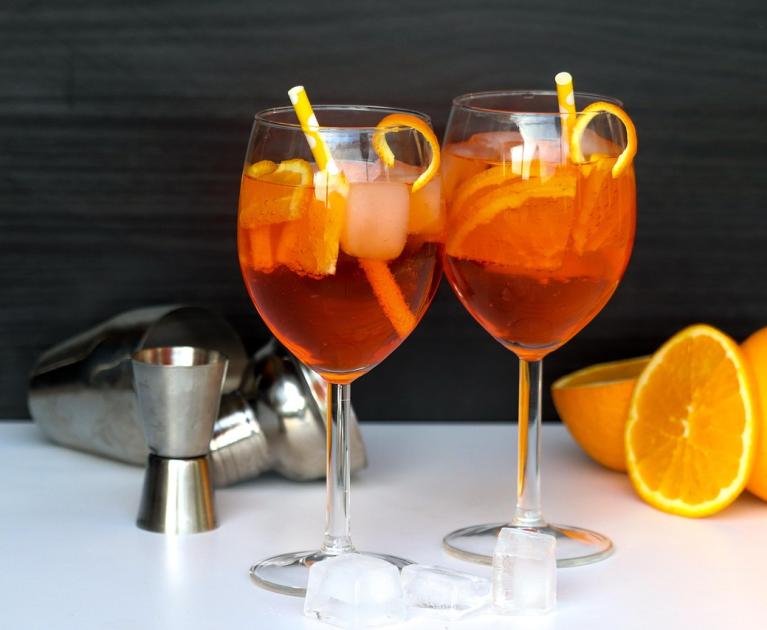 Two orange spritz with ice and oranges, fresh and lively atmosphere.