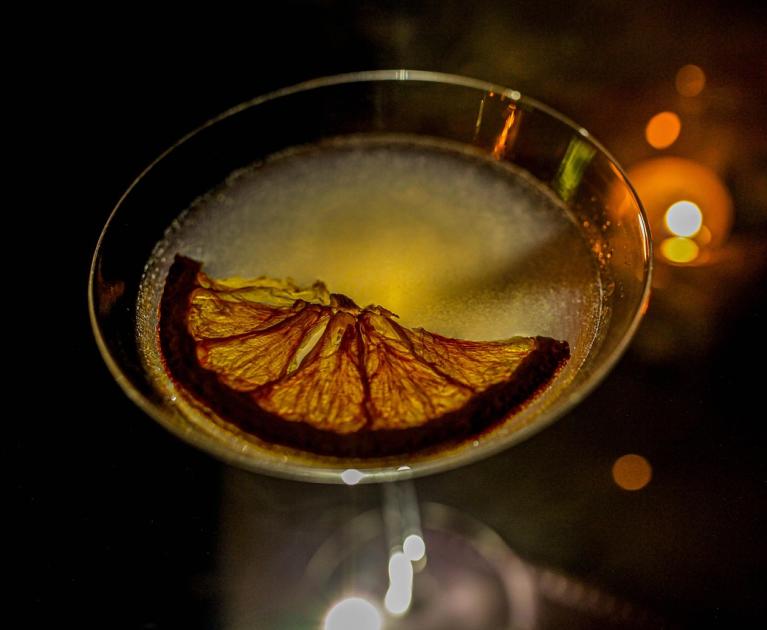 Elegant cocktail with dried orange slice, warm and glowing atmosphere.