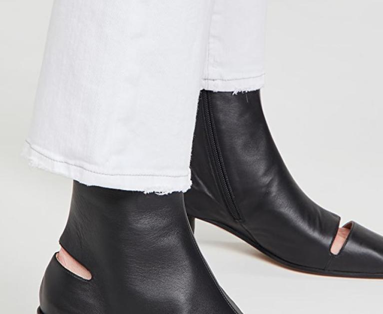 Chic black boots with cutouts on white pants. Modern and stylish.