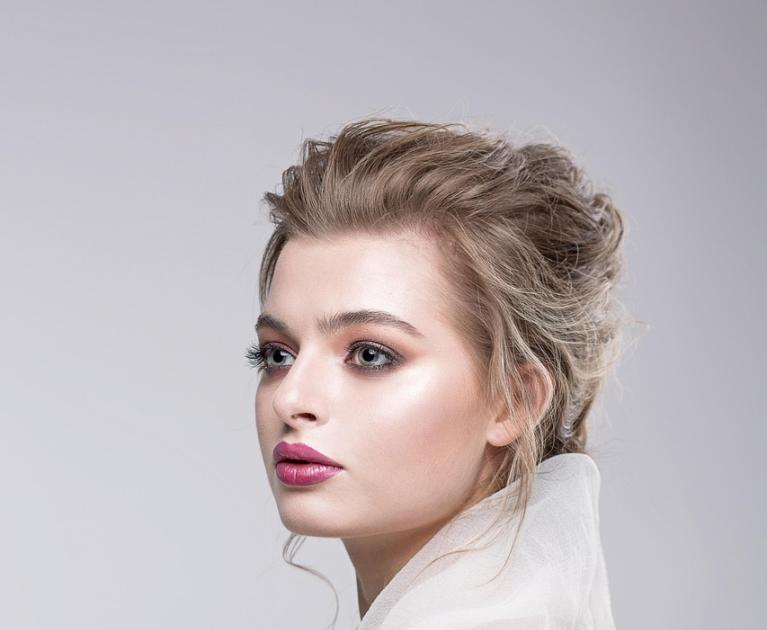 Elegant woman in sheer white dress, intense and sophisticated gaze.