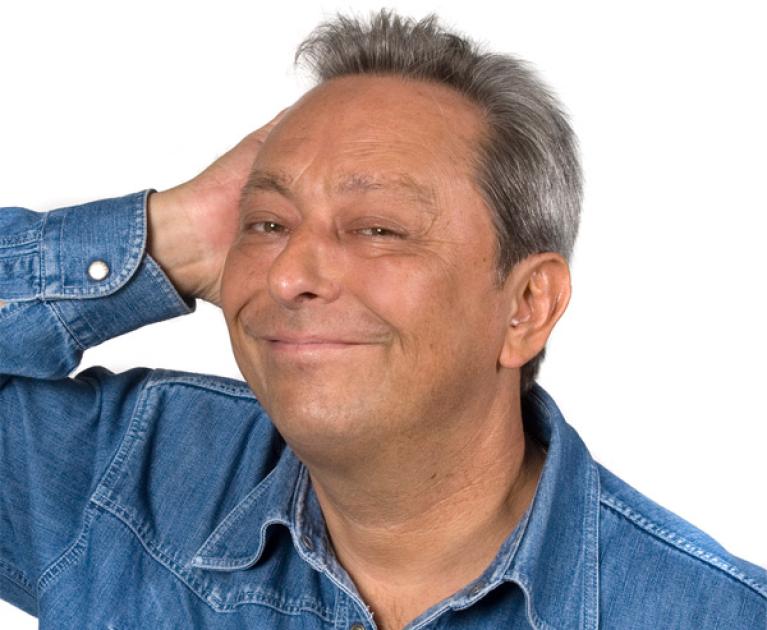 Smiling man in denim shirt, conveys friendliness and calmness.