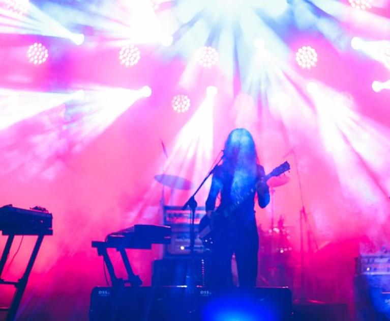 Vibrant concert, colorful lights, lone musician plays guitar in a magical atmosphere.