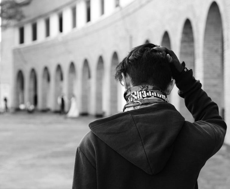Reflective person in an arched courtyard, atmosphere of solitude and contemplation.