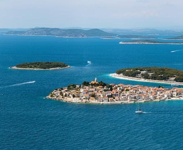 Picturesque island in blue sea, elegant boats, serene landscape.